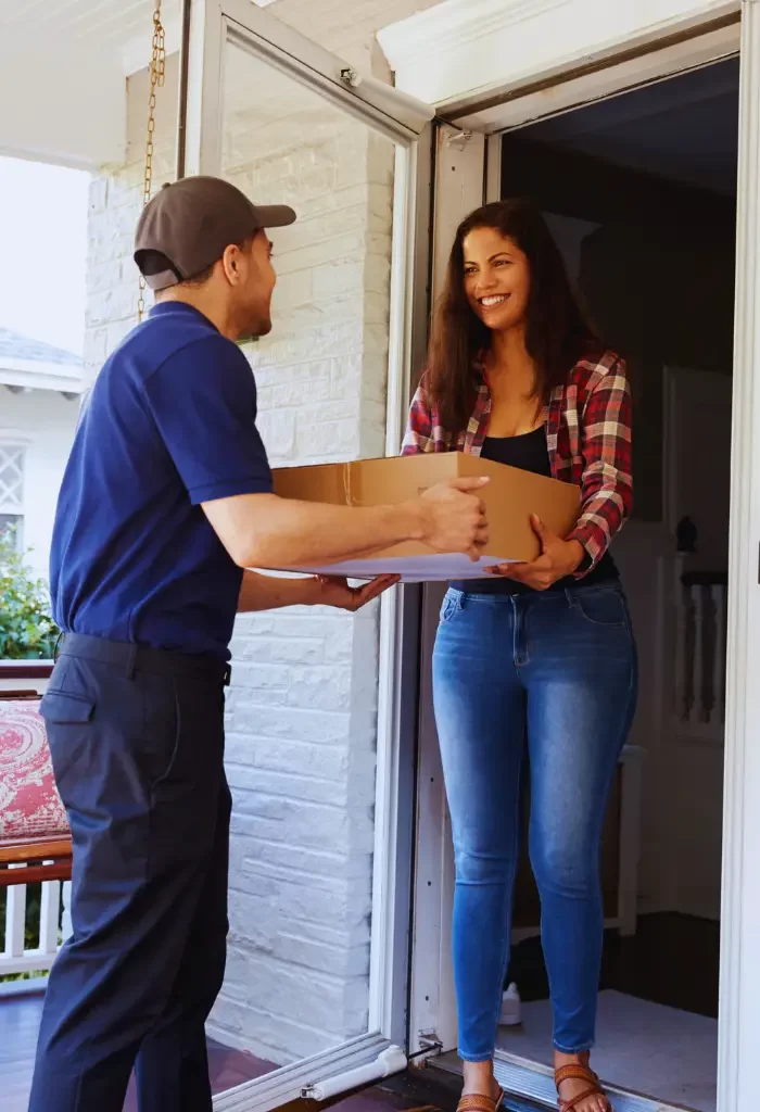 Delivery person handing over a package to a smiling woman at her doorstep.