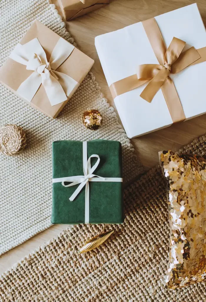 Elegantly wrapped gift boxes with ribbons and golden accents on a woven mat.